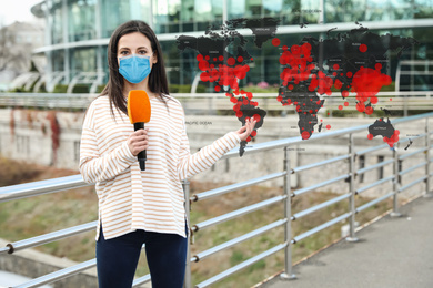 Journalist with medical mask presenting news during coronavirus outbreak. World map demonstrating spread of disease