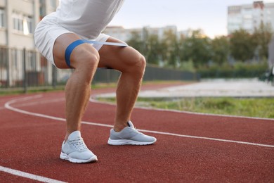 Photo of Muscular man doing exercise with elastic resistance band at stadium, closeup