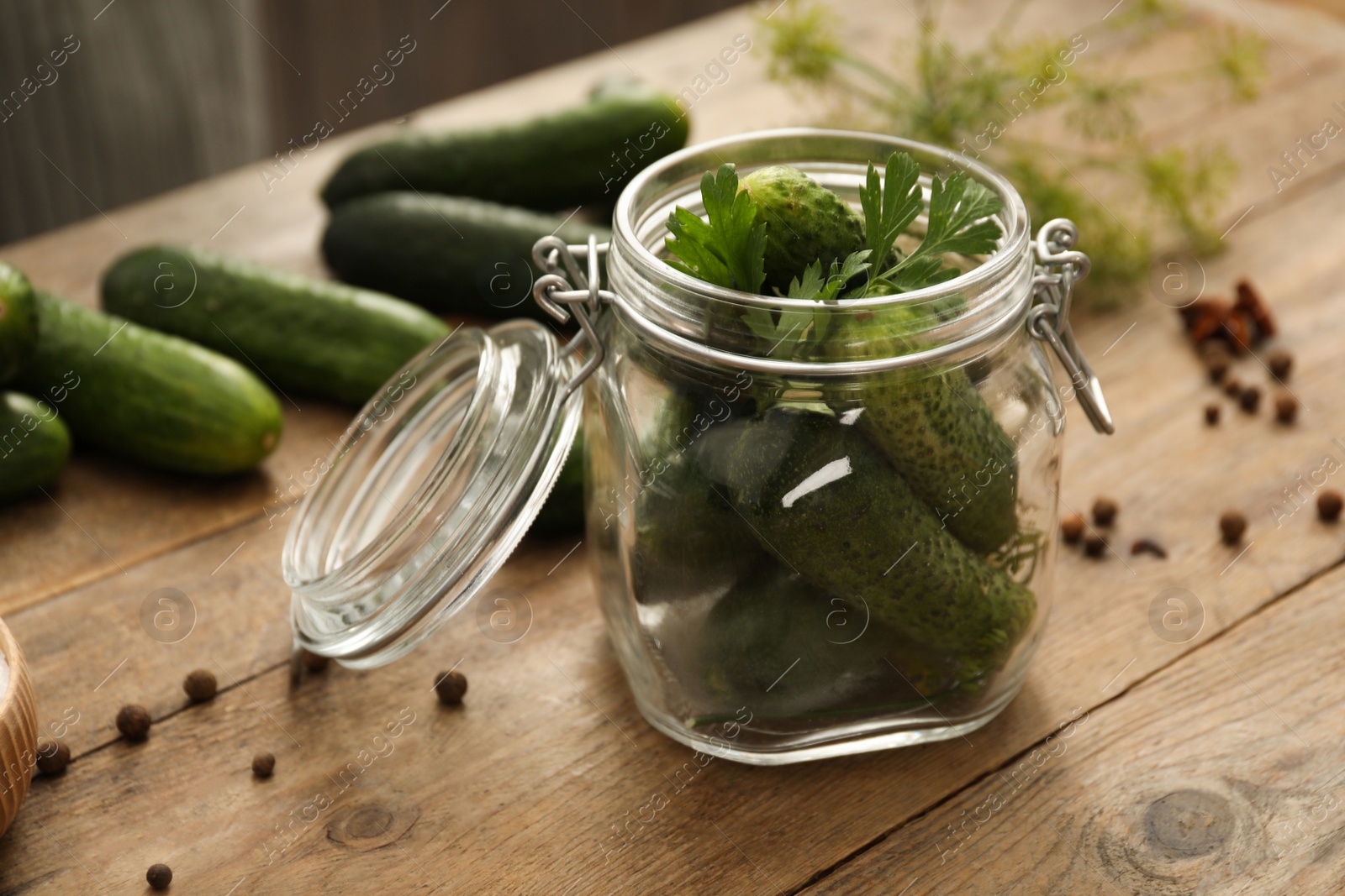 Photo of Pickling jar with fresh cucumbers on wooden kitchen table, closeup