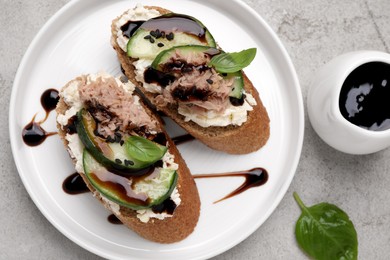 Photo of Delicious bruschettas with balsamic vinegar and toppings on light textured table, flat lay
