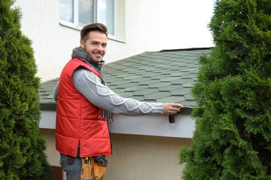 Photo of Young man decorating roof with Christmas lights