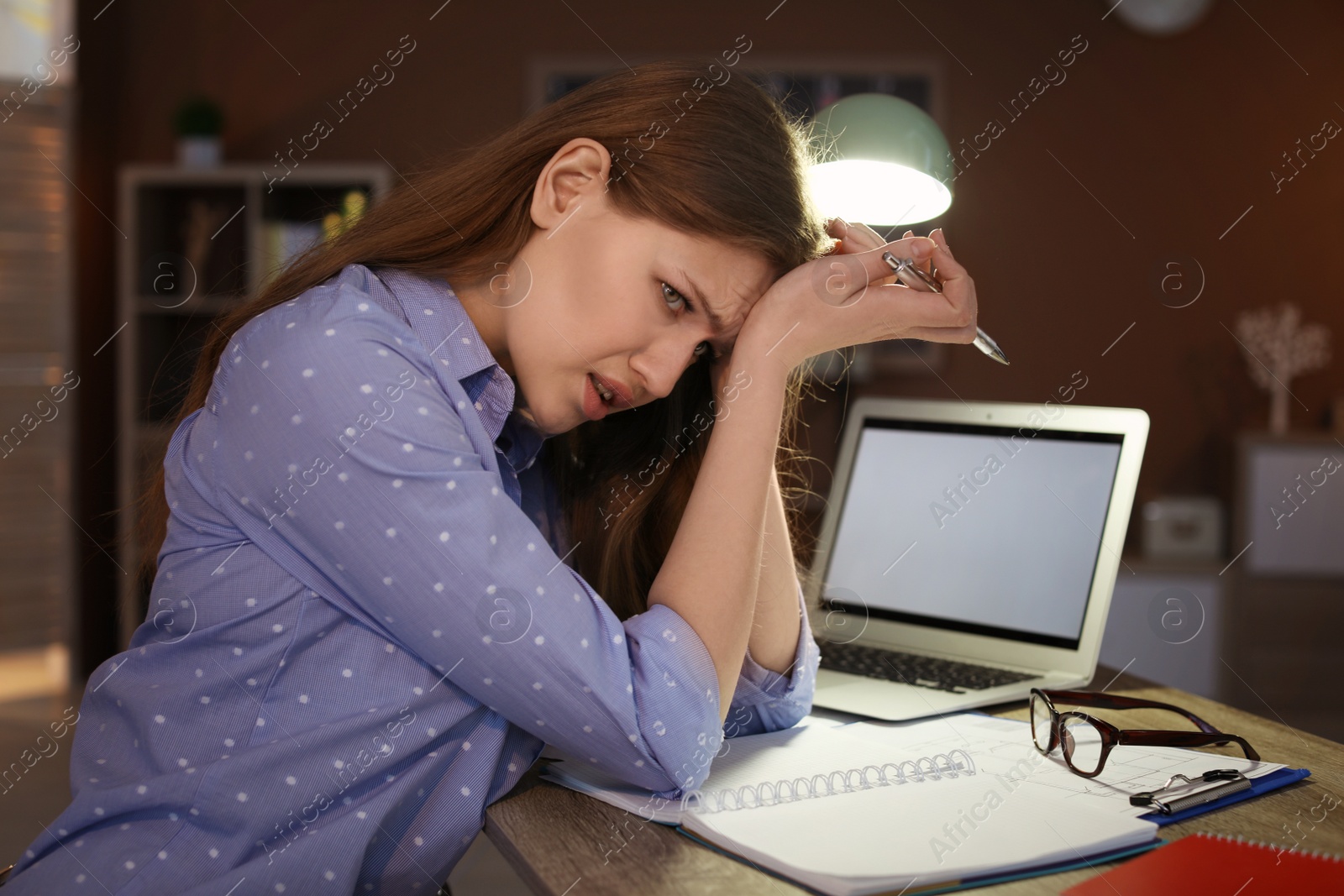 Photo of Overworked young woman with headache in office