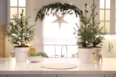 Photo of Small Christmas trees and festive decor in kitchen