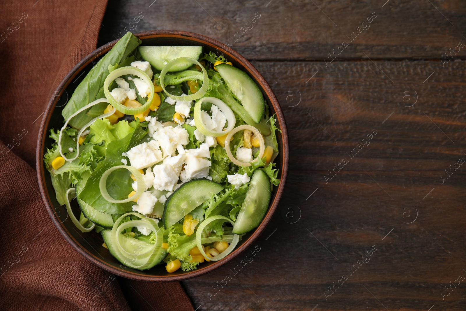 Photo of Bowl of tasty salad with leek and cheese on wooden table, top view. Space for text