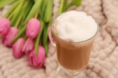 Photo of Glass of delicious cocoa and pink tulips on light blanket, closeup