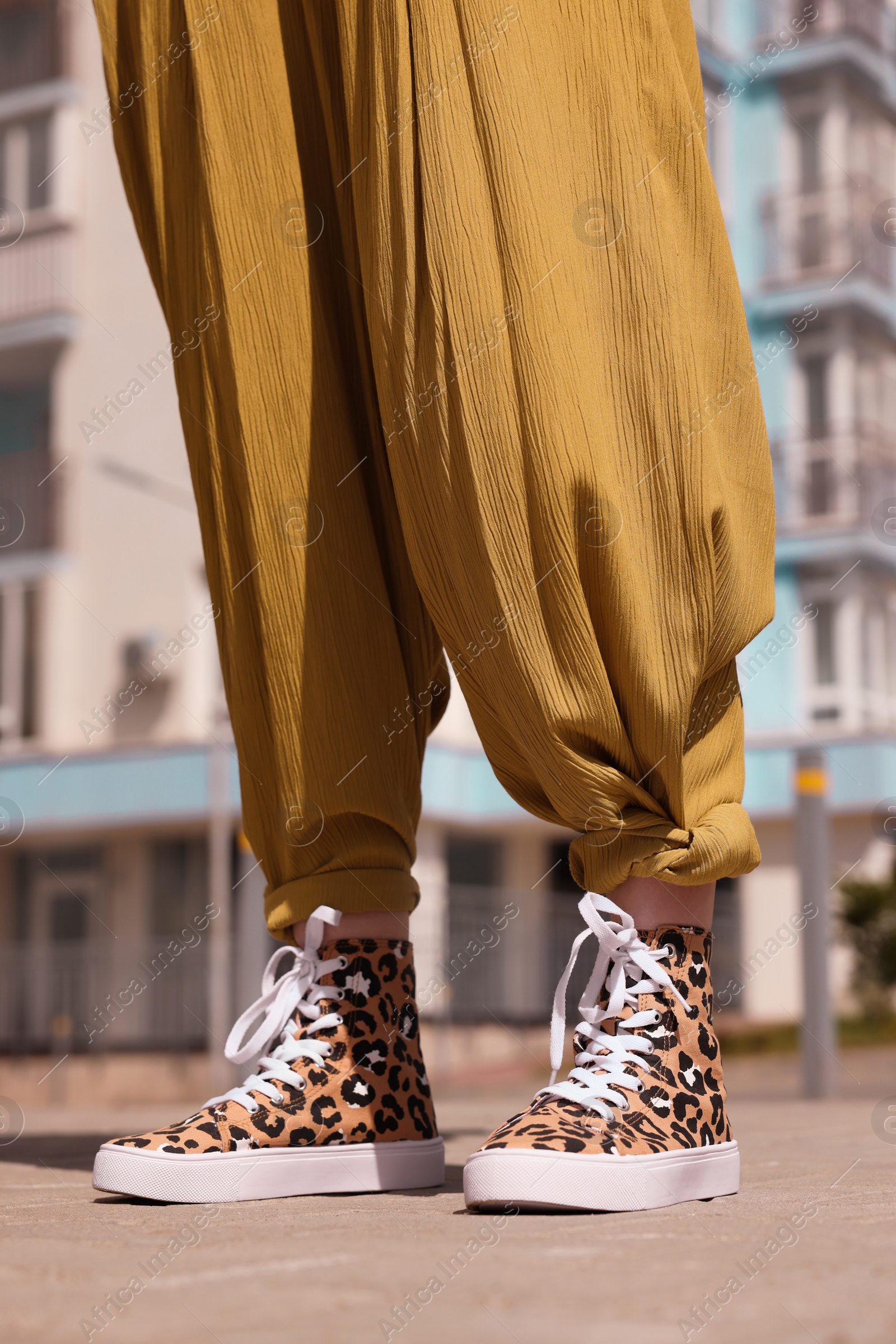 Photo of Woman wearing sneakers with leopard print outdoors, closeup