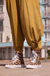 Woman wearing sneakers with leopard print outdoors, closeup