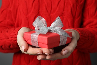 Photo of Christmas present. Woman holding gift box against grey background, closeup