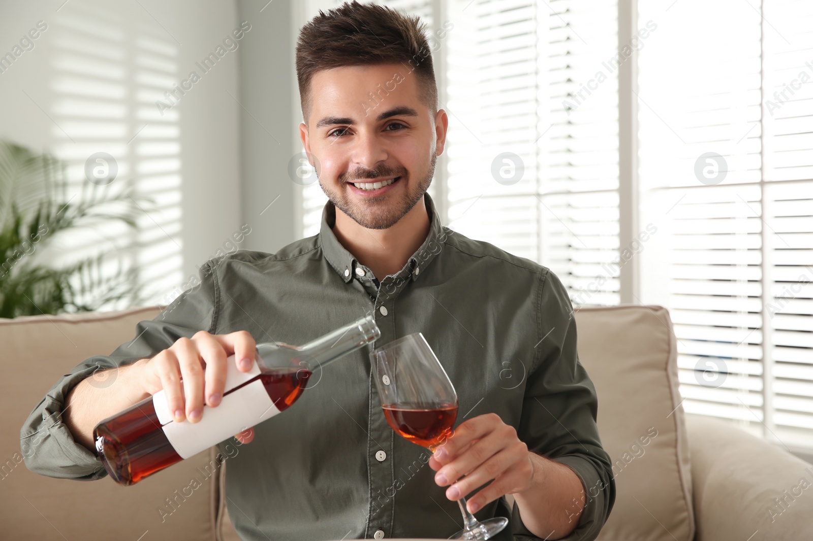 Photo of Man drinking wine while having online video conference at home, view from web camera. Social distancing during coronavirus pandemic