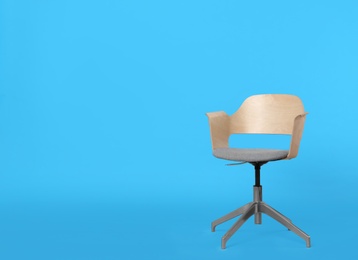 Photo of Comfortable office chair on light blue background, space for text