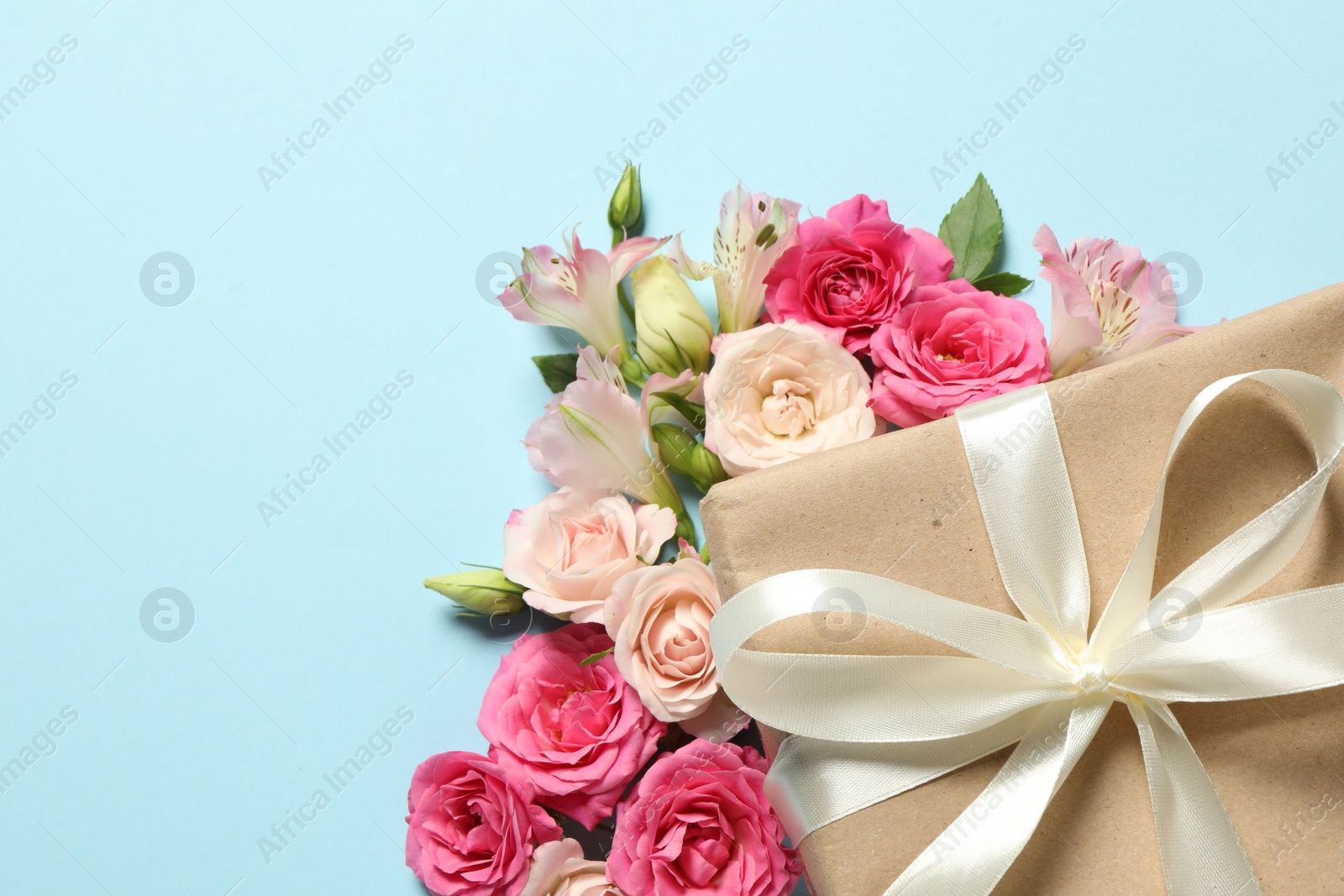 Photo of Happy Mother's Day. Beautiful flowers and gift box on light blue background, flat lay. Space for text