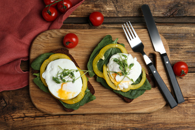 Photo of Delicious poached egg sandwiches served on wooden table, flat lay