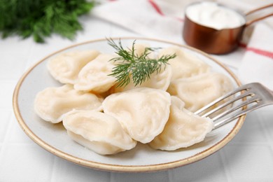 Photo of Cooked dumplings (varenyky) with tasty filling and dill on white table, closeup