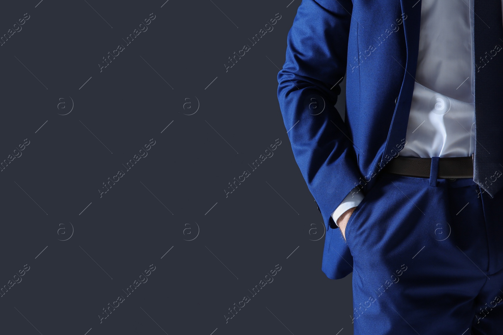 Photo of Businessman holding hand in pocket on dark background. Space for text