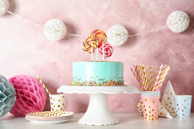 Stand with fresh delicious cake and birthday decorations on table