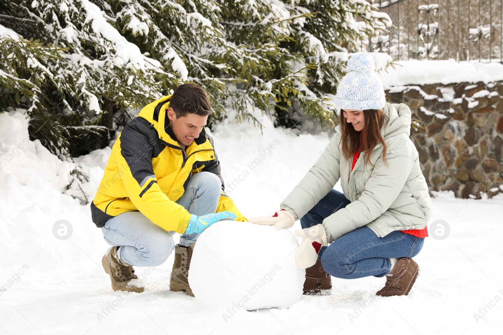 Photo of Happy couple making ball for snowman outdoors. Winter vacation