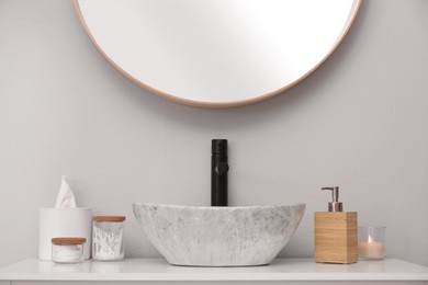 Photo of Wooden dispenser of liquid soap and toiletries near sink in bathroom