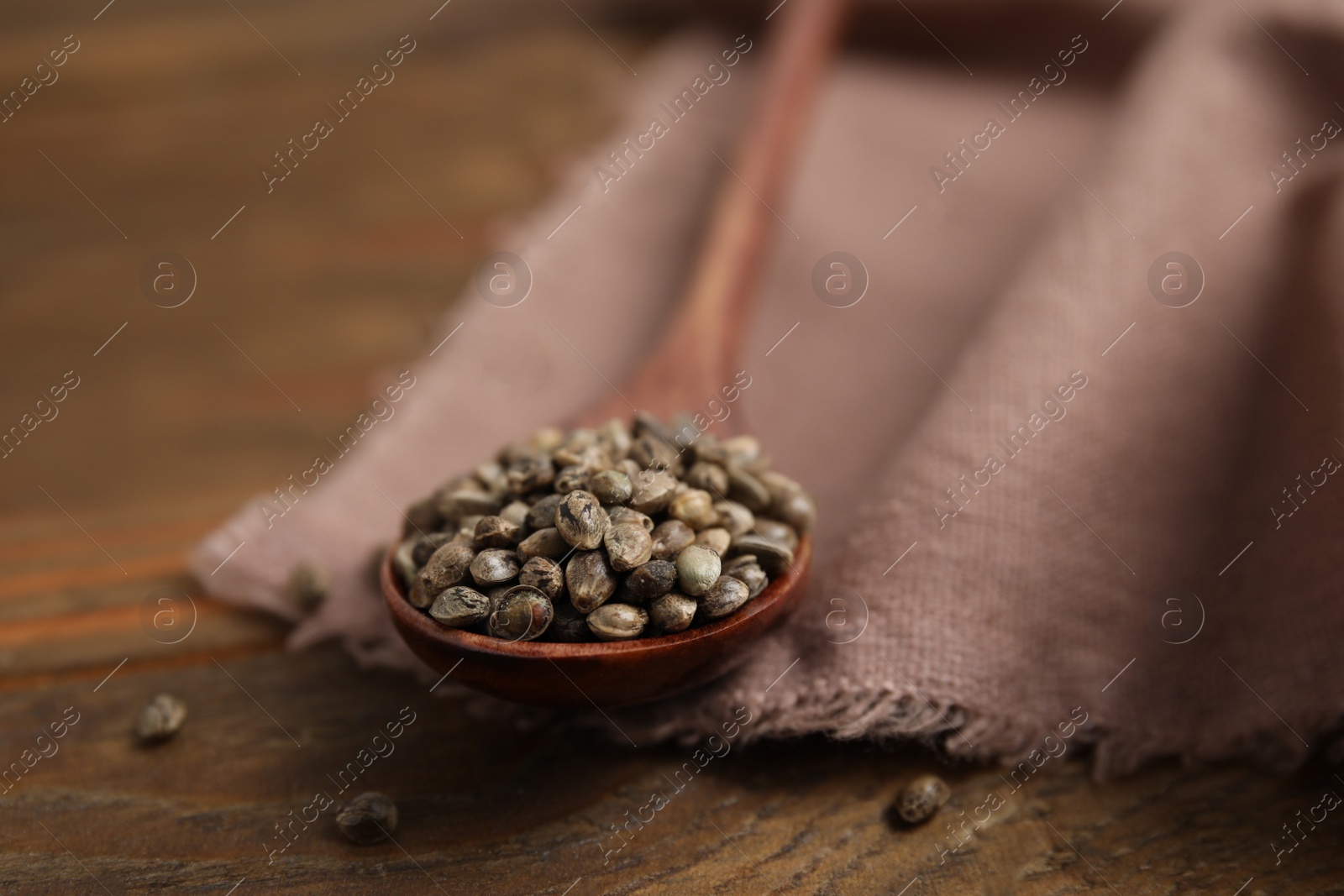 Photo of Spoon with organic hemp seeds on wooden table, closeup