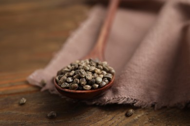 Spoon with organic hemp seeds on wooden table, closeup