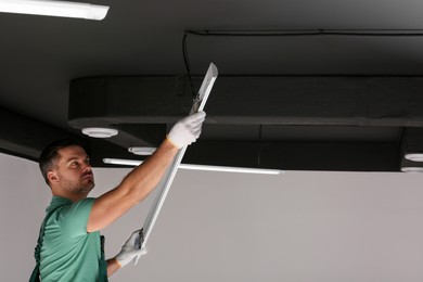 Photo of Ceiling light. Electrician installing led linear lamp indoors. Space for text