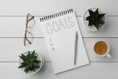 Photo of Planning concept. Flat lay composition with empty list of goals in notebook and glasses on white wooden table