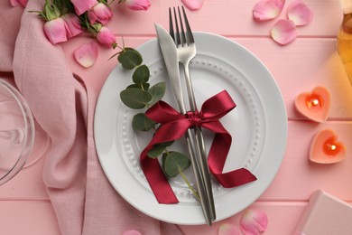 Photo of Place setting with heart shaped candles and bouquet of roses on pink wooden table, flat lay. Romantic dinner