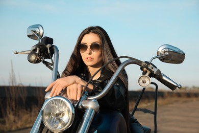Beautiful young woman sitting on motorcycle outdoors