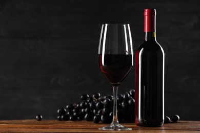 Photo of Delicious wine and ripe grapes on wooden table. Space for text