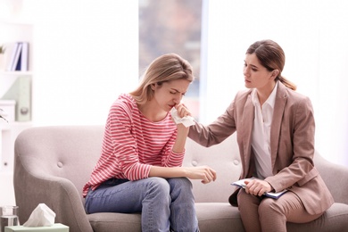 Photo of Psychotherapist working with young woman in light office