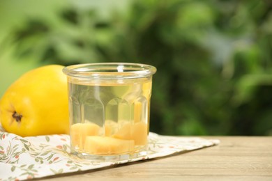 Photo of Delicious quince drink and fresh fruit on wooden table against blurred background. Space for text