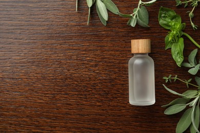 Photo of Bottle of essential oil and fresh herbs on wooden table, flat lay. Space for text