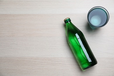 Photo of Glass and bottle with water on wooden background, flat lay. Space for text