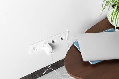 Photo of Electric power outlet sockets with charger on white wall