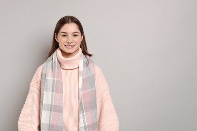 Photo of Beautiful woman in warm scarf on gray background, space for text