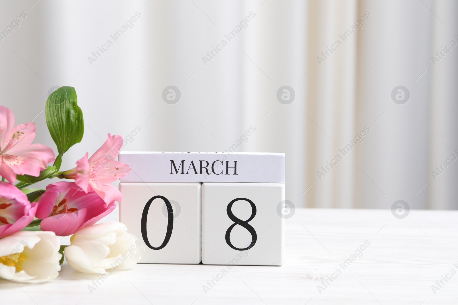 International Women's day - 8th of March. Wooden block calendar and beautiful flowers on white table, space for text Photo of International Women's day - 8th of March. Wooden block calendar and beautiful flowers on white table, space for text