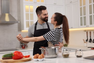 Photo of Happy lovely couple dancing together while cooking in kitchen