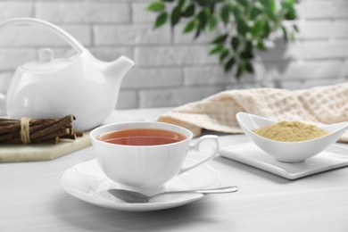 Photo of Aromatic licorice tea in cup served on white table