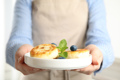 Photo of Woman with plate of delicious cottage cheese pancakes, closeup