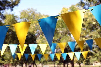Photo of Colorful bunting flags in park. Party decor