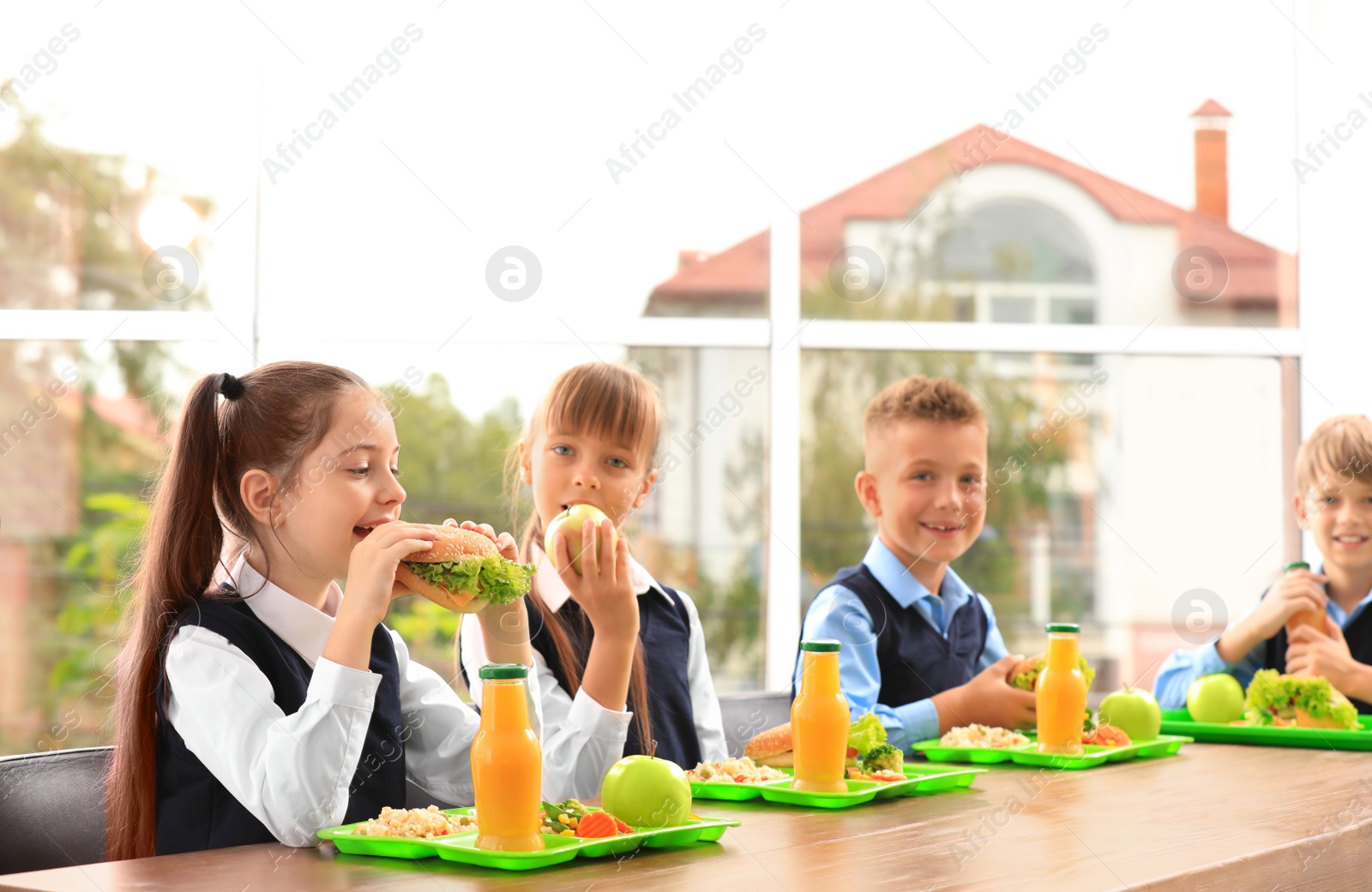 Photo of Happy children at table with healthy food in school canteen