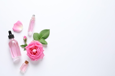 Photo of Composition with rose essential oil and flowers on white background, top view