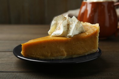 Photo of Piece of delicious pumpkin pie with whipped cream on wooden table, closeup