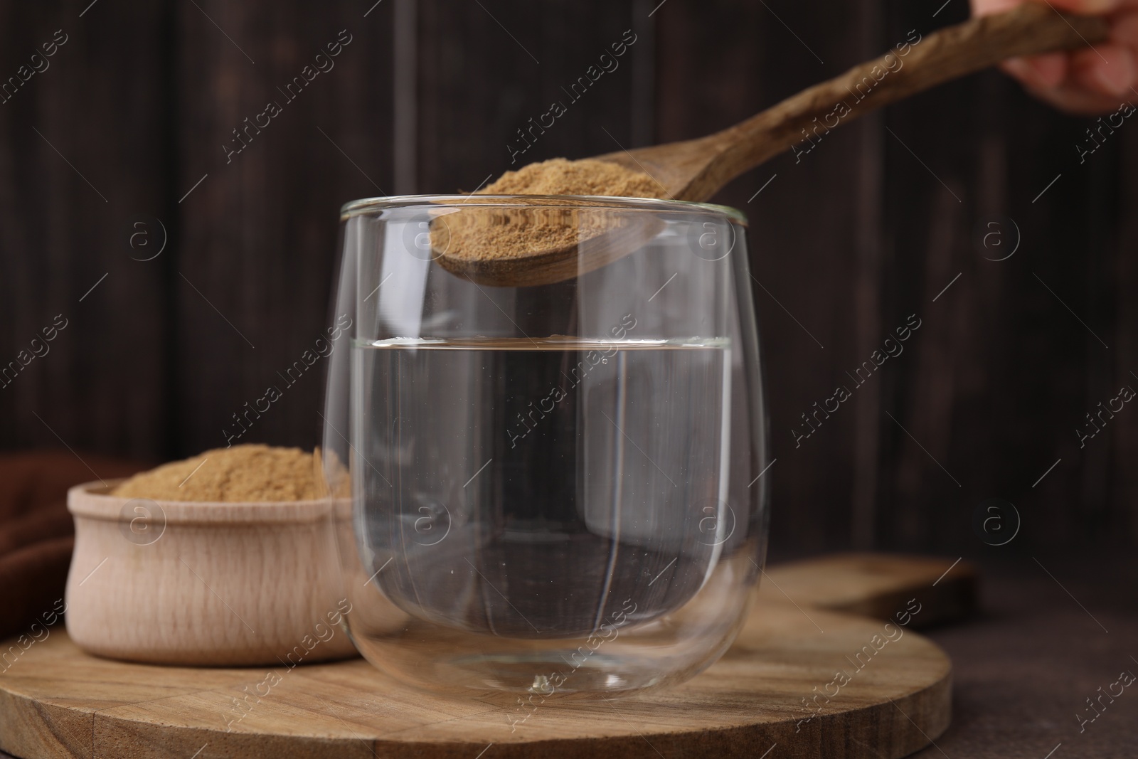 Photo of Dietary fiber. Woman adding psyllium husk powder into water at table, closeup