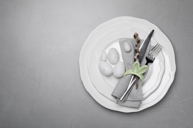 Photo of Festive table setting with painted eggs and willow twig on light grey background, top view with space for text. Easter celebration