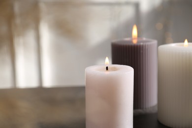 Photo of Different burning candles on grey table indoors. Space for text