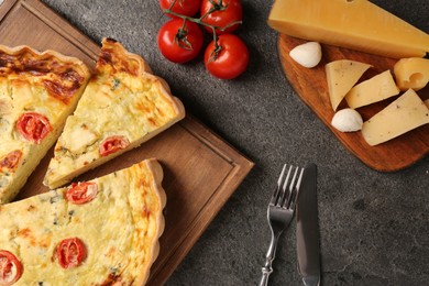 Photo of Delicious homemade cheese quiche, cutlery and ingredients on gray table, flat lay