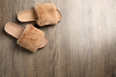 Photo of Pair of soft slippers on wooden background, flat lay. Space for text