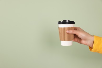 Photo of Woman holding takeaway cup with drink on pale green background, closeup view and space for text. Coffee to go