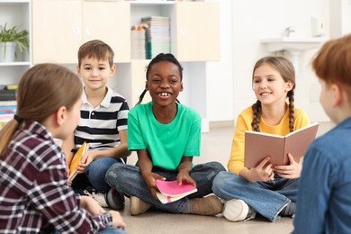 Photo of Cute children discussing homework in classroom at school