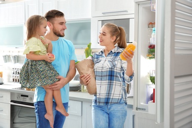 Photo of Happy family putting products into refrigerator in kitchen